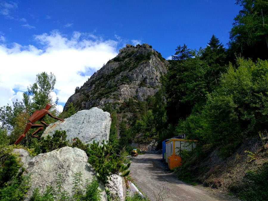 Sculpture of a climber and approach path with the via ferrata wall in the background 
