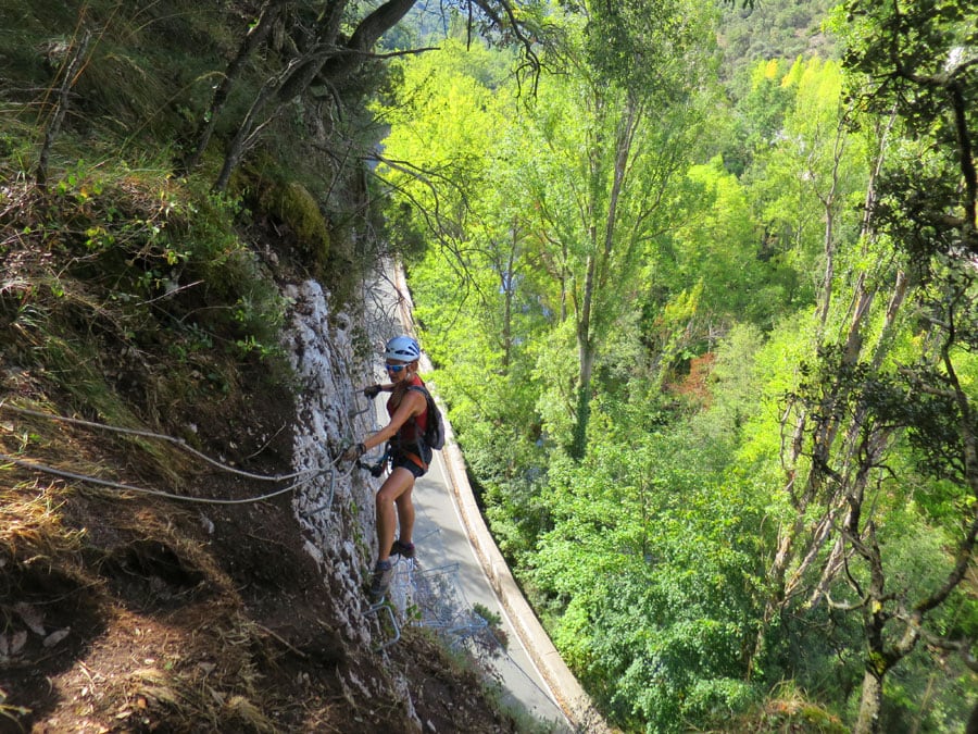 Continuamos bordeando la pared del roquero entre vegetación sin dificultad. Bajamos por una pared sobre la carretera BU-561 que le da sensación aérea y en avance lateral nos ayudamos de grapas y roca 