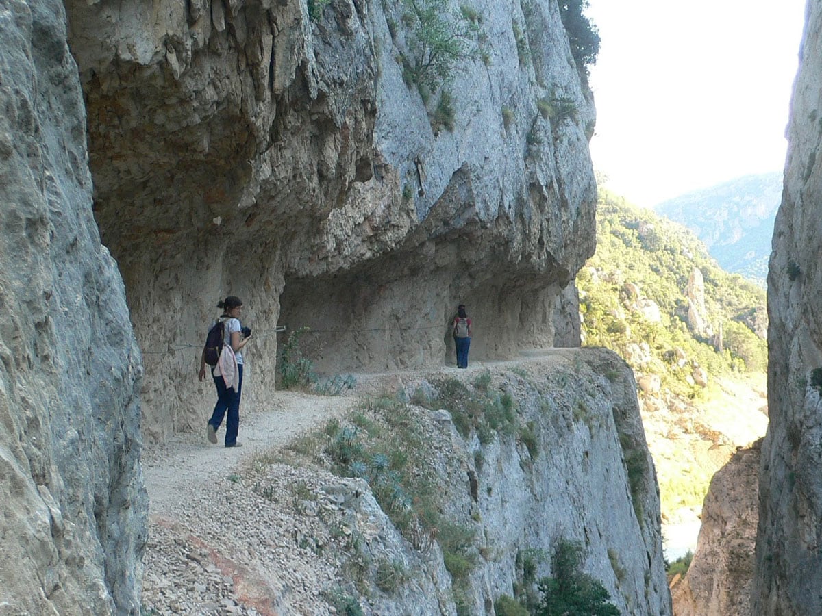 Walking on a ledge sculpted in the rock very high above the water 