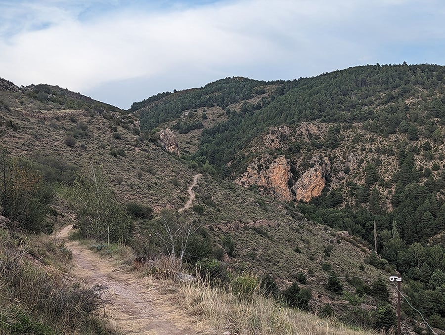 Camino de aproximación y afloramiento rocoso a la izquierda por donde sube la vía ferrata 