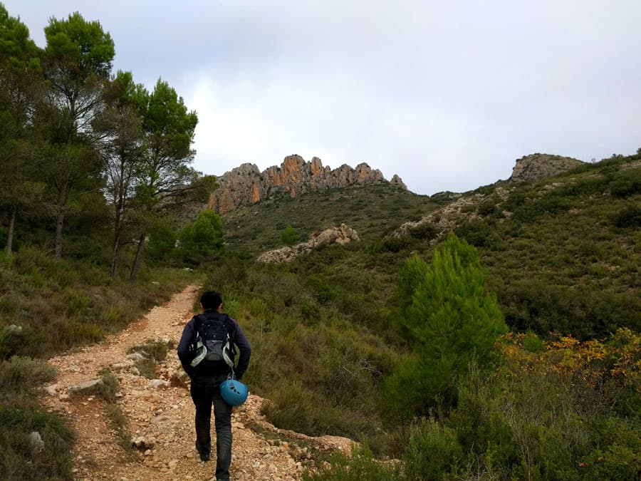 Camino de aproximación con la pared de la vía ferrata visible al fondo con sus agujas características