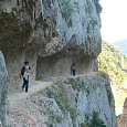 Walking on a ledge sculpted in the rock very high above the water 