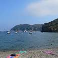 Playa de piedras de la Cala Jòncols con el Cap de Norfeu al fondo 